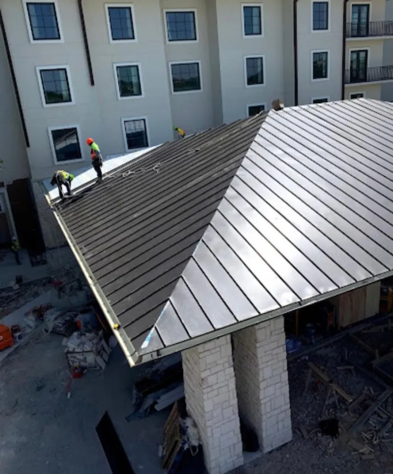 Crew installing standing seam metal roof panels on a commercial project in Micco